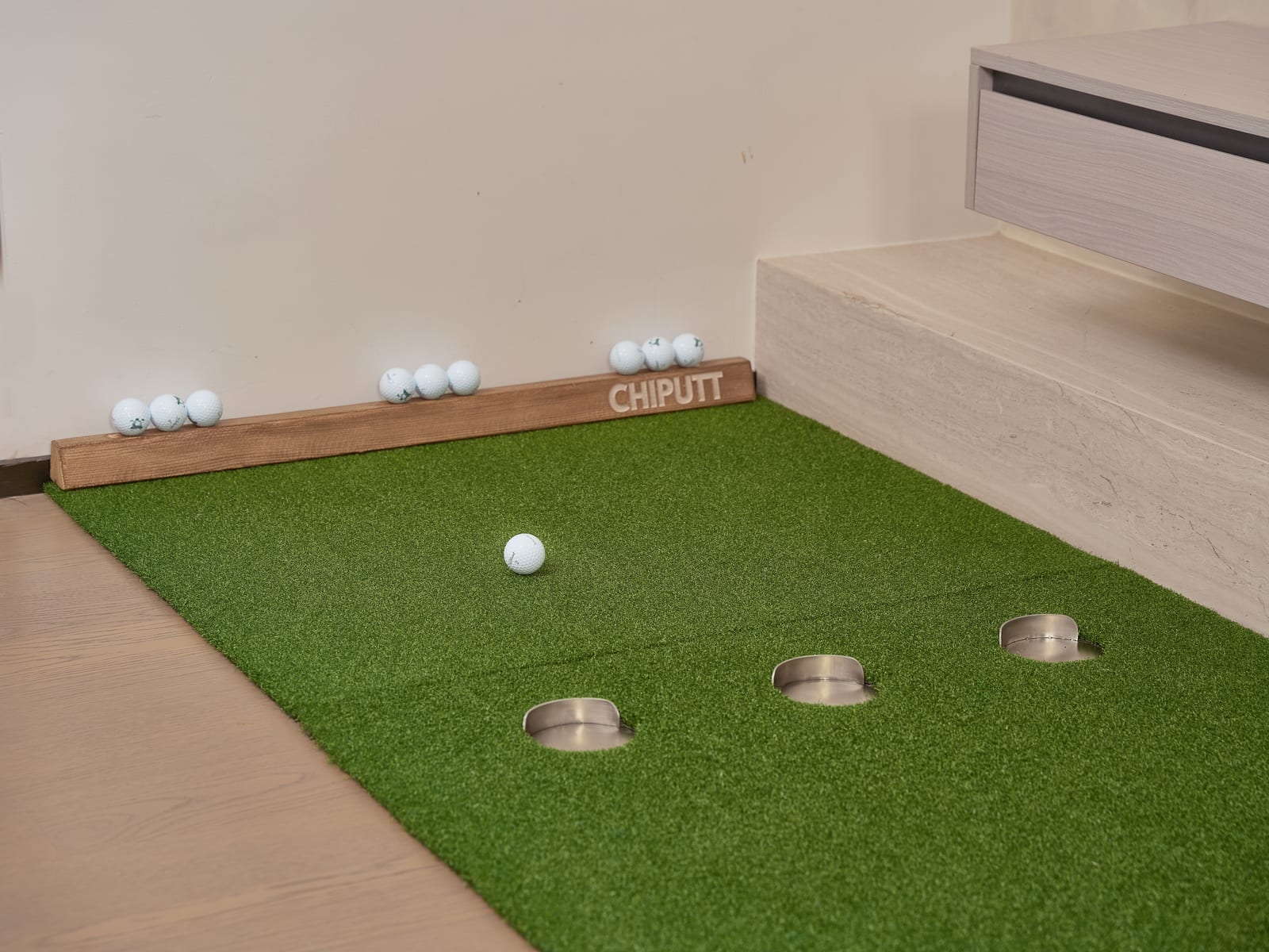 A golf simulator bay with the screen lit and a mat on the floor.